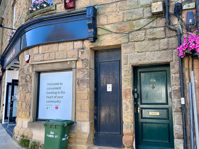 A bank building with a welcoming sign and a green door at Downton I Alnwick