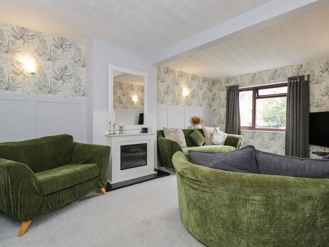 A living room with green sofas and a mirror at 1 Stanway Road