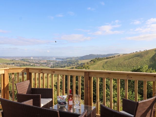 A deck with a table and chairs overlooking a valley at Lodge 19 in Torpoint
