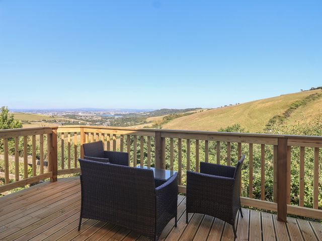 A deck with chairs and a table overlooking hills at Lodge 19 in Millbrook