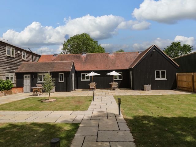 A black house with a patio and tables under umbrellas at Poppy Patch in Stratton Audley near Bicester