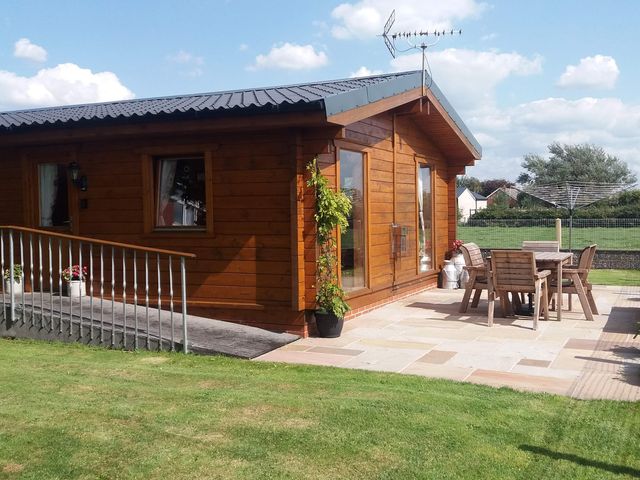 A log cabin with a patio and seating area at Chestnut Lodge in Pilling