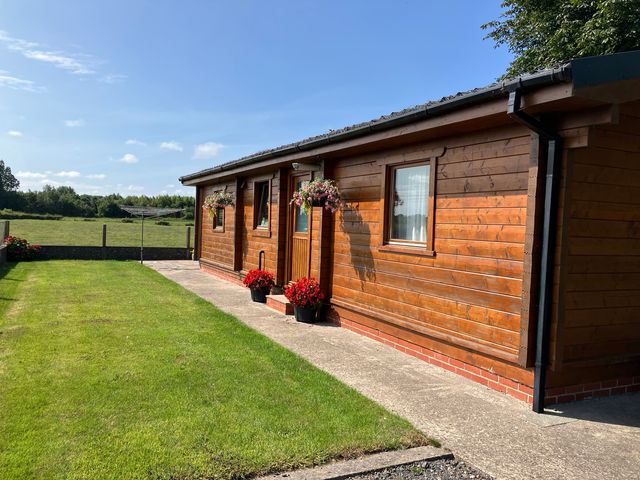 A cabin with a pathway and flower pots at Chestnut Lodge in Pilling