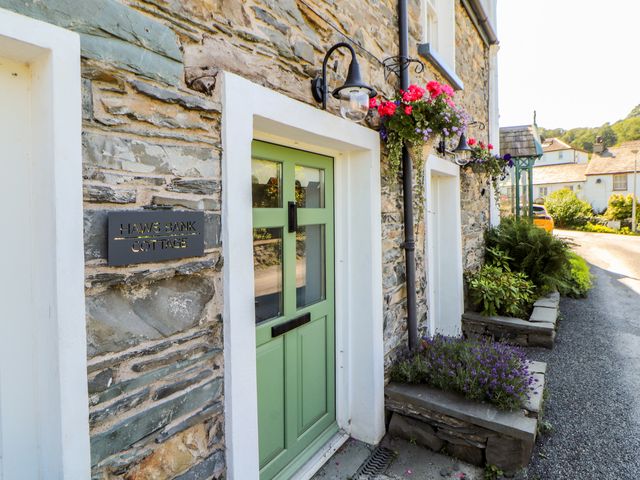 An entrance of Haws Bank Cottage with flowers and sign in Coniston