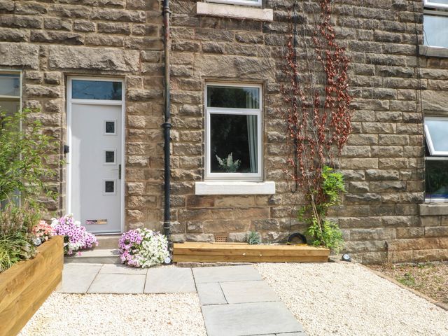 A front entrance with a door and window beside a floral garden at 2 Bentley Bridge Cottages Matlock