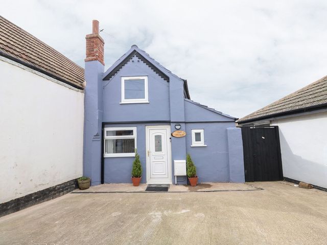 The exterior of Oar Cottage in Mablethorpe with a blue facade and plants by the door