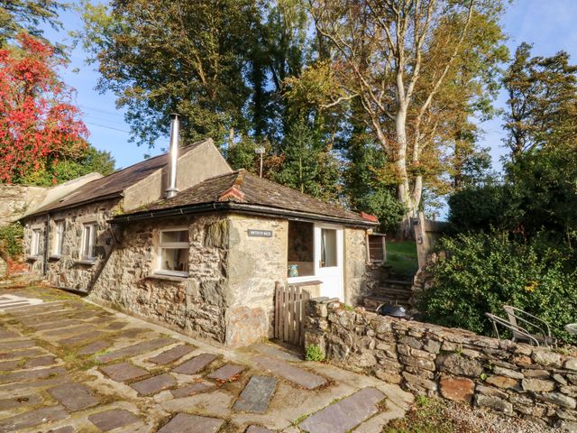 A stone cottage with a pathway and garden at Bwthyn Bach in Pentrefelin