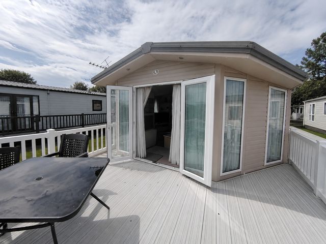 An outdoor area with sliding doors and a table at Marine Holiday Park - 21NC Rhyl