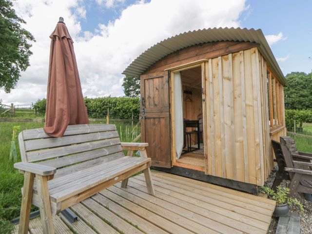 A hut with a wooden deck and umbrella at The Little Shepherds Hut with a View Builth Wells