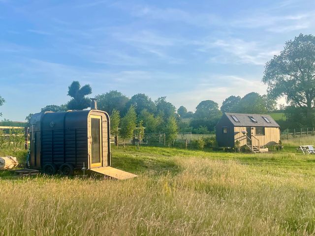 A wooden cabin and portable cabin on a grass area at Cloud Cabin Gillow Heath near Biddulph