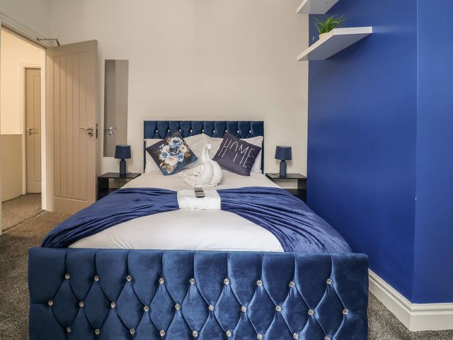 A bedroom with a blue bed and bedside tables at Lunt Road in Bootle