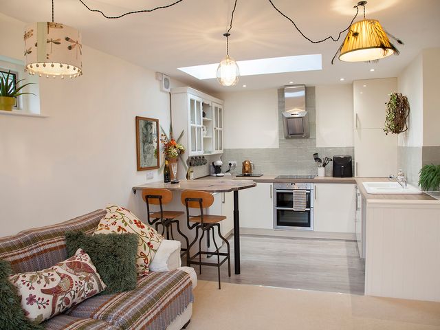 A kitchen with bar stools and cabinets at Snug Cottage in Honley