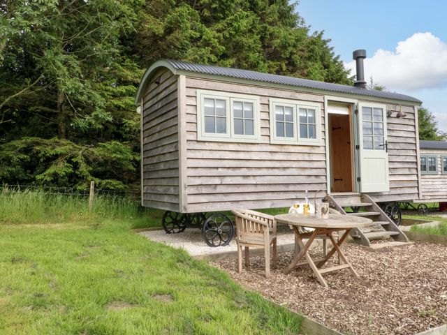 A shepherd's hut with table and chairs outside at Pike House Farm Shepherds Hut 1 in Asbourne