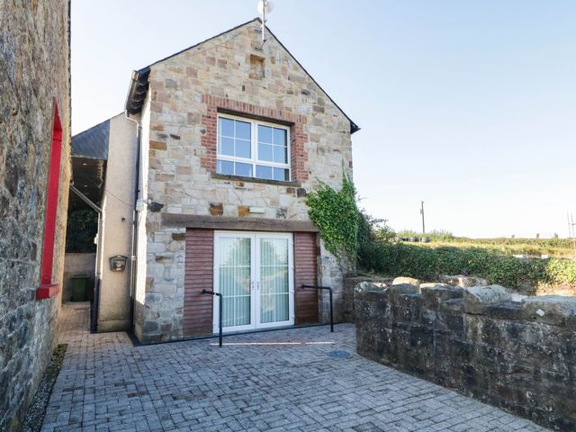 A stone building with a patio and large window at The Mummers Studio Apartment 1, Derrylin, County Fermanagh