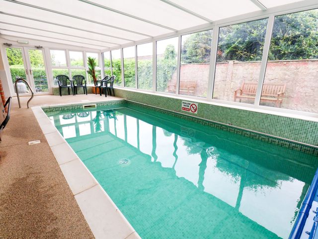 An indoor swimming pool with chairs and a bench at Owl in Pickering