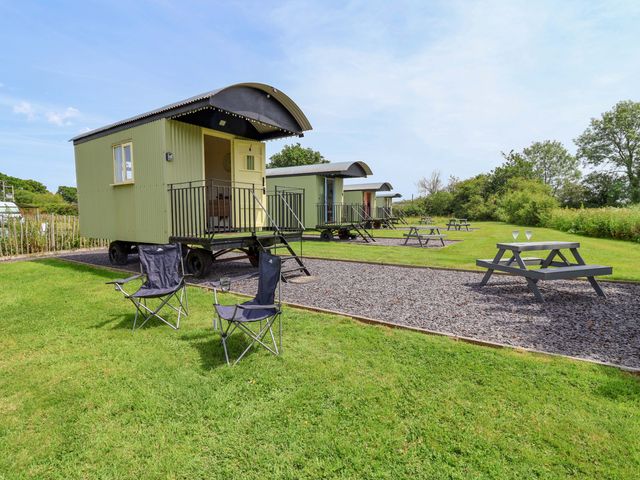 Huts with picnic tables and chairs at Bee Happy Whitchurch