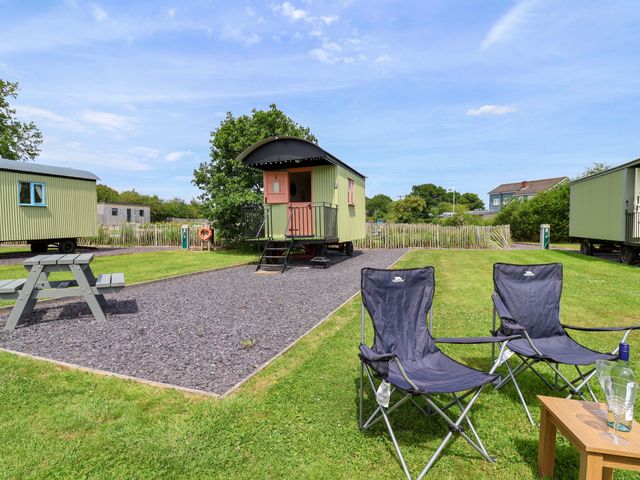 An outdoor area with caravans and seating at Foxes Den in Whitchurch