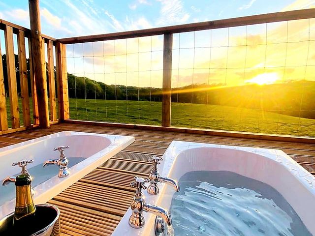 A deck with bathtubs and sunset view at a property in the countryside