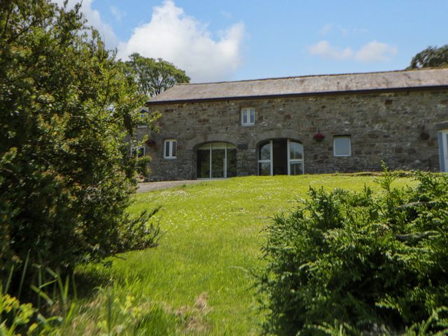 A stone building with windows and a door in a garden at The Cart House in Pontsian