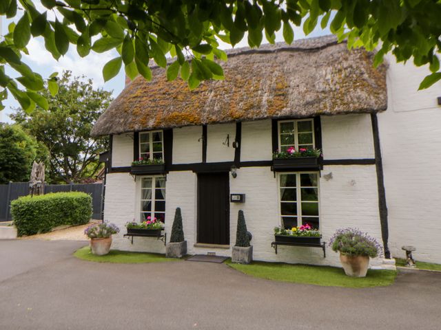 A cottage with a thatched roof and plants at Eightlands Hereford