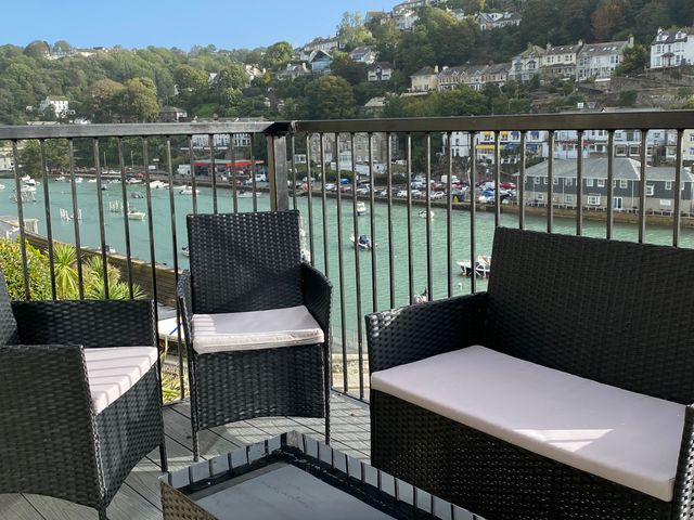 A balcony with chairs and a table overlooking a body of water at Rivercrest in Looe