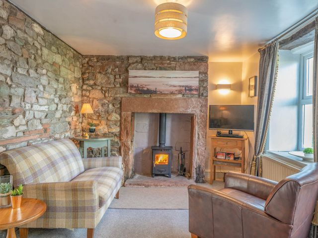 A living room featuring a fireplace and two seating areas at Cosy cottage near scenic walks and country pub in Penrith