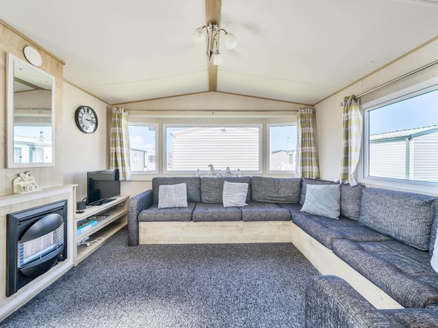 A living room with a sofa and television at Sleeps 8 Communal Spa Access Parking Rhyl