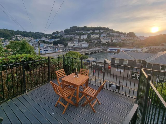 An outdoor seating area with a table and chairs overlooking the harbor at Looe Cottage Seaside views log fire sleeps 4, Looe