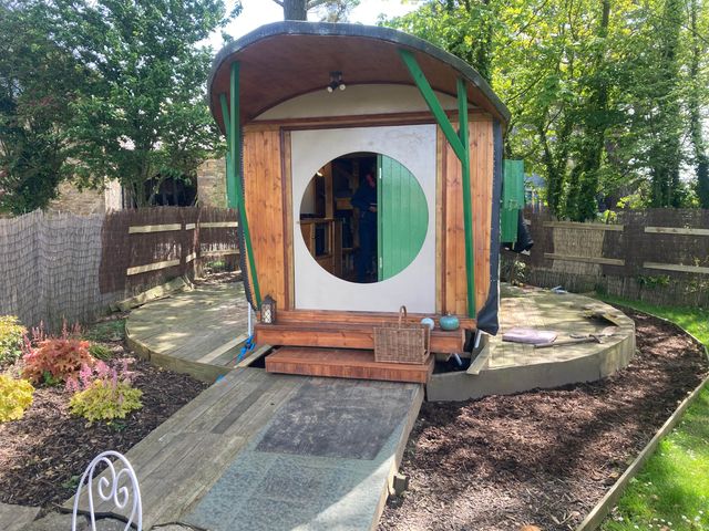 A wooden structure with a round door in a garden at The Owl House in countryside setting Near Niwbwrch (newborough)