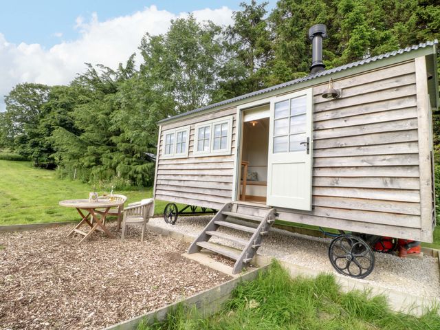 A shepherd hut with a table and chairs outside at Pike House Farm Shepherds Hut 2 Ashbourne