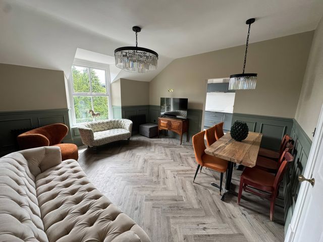 A living room with a sofa and dining area at The Buxton Suite in Buxton