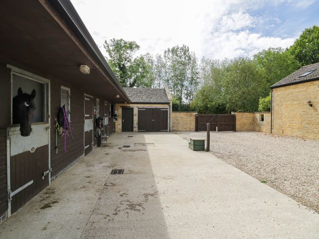 An outdoor horse stable area with a horse and wooden doors at Wayside in Moreton-in-Marsh