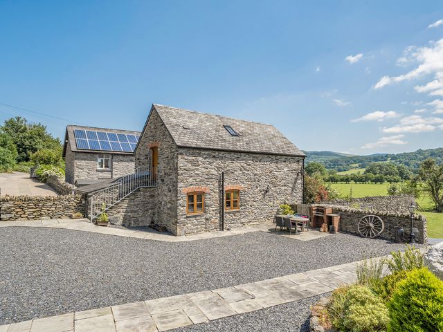 A stone house with a gravel driveway and solar panels at The Granary in Corwen