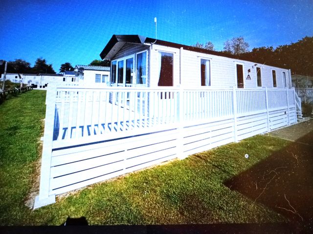 A mobile home with a deck and fence at Hedley Wood Park-Duckpool8 in Holsworthy