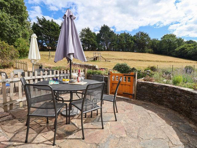 A garden with a table and chairs under an umbrella at Iris at Stancombe Manor Sherford near Chillington