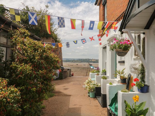 A pathway with hanging flags and flower pots at Tower View Cottage in Lympstone