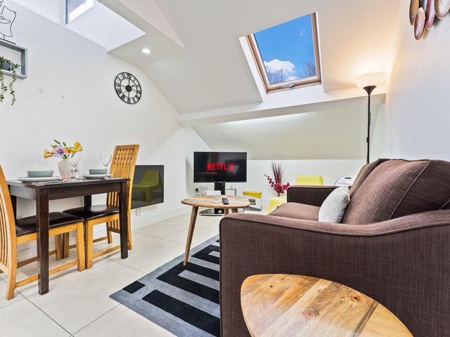 A living room with dining furniture and a television at 5 Pump House in Birmingham