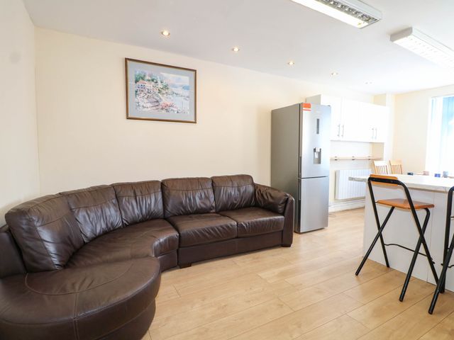 A living room with a sofa and refrigerator at 90 A Station Road in New Milton