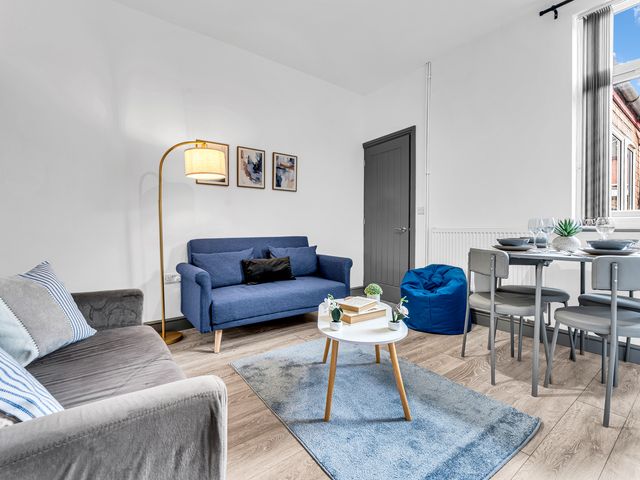 A living room featuring a sofa, dining table and a lamp at Victoria House, Stoke on Trent
