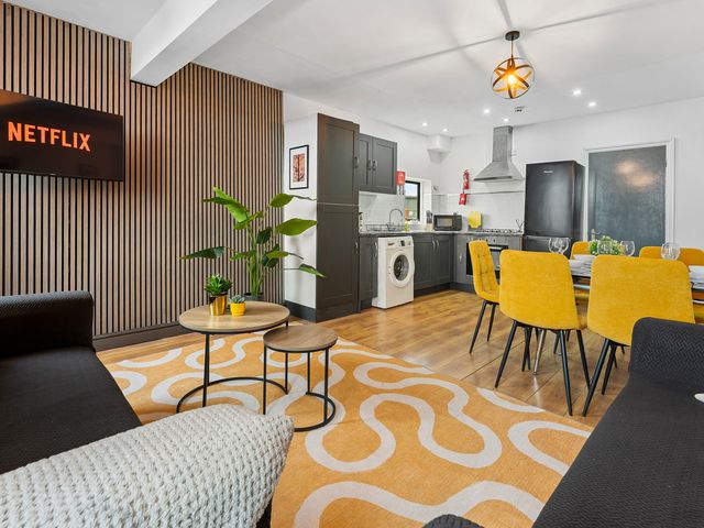 A living room with a dining area and kitchen appliances at The Craftsman Birmingham City Apartment in Birmingham
