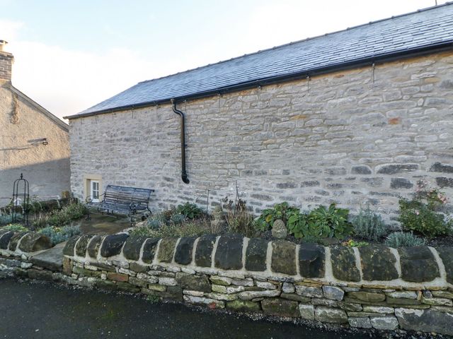 An outdoor area with a stone wall and bench at Laneside Barn Calver