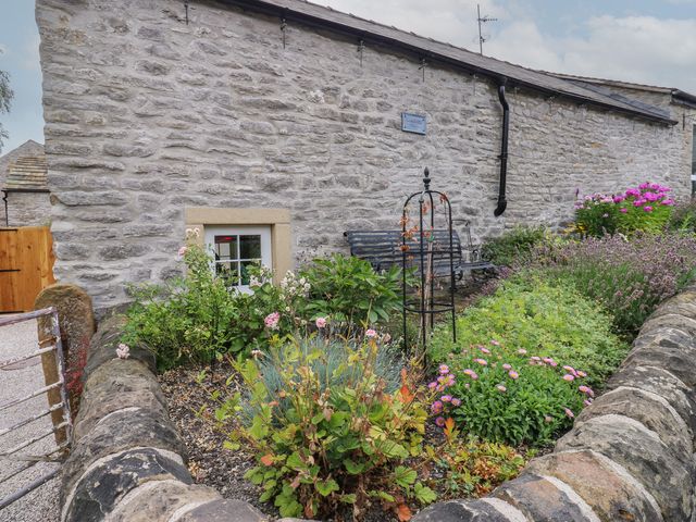 A garden with flowers and a bench at Laneside Barn in Calver