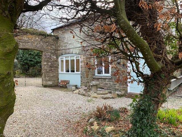 An outdoor view of a cottage with a stone wall and garden at 1 bed cottage Parking Patio close to coasts Coads Green near Launceston