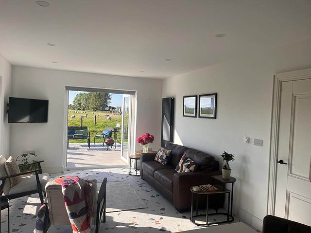 A living room with a sofa and television at Sunset Cottage Sleeps 6 with Parking Garden Magilligan near Limavady