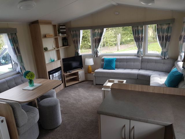 A living room with a sofa, table, and television at Caravan Sleeps4 Pet friendly with Parking Available in Skegness