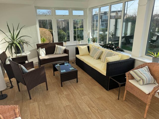 A conservatory with seating and plants at House Sleeps 8 Close to Beach Free parking in Mullion