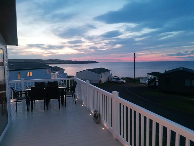 A table and chairs on a deck overlooking the sea at Seaside Lodge Retreat in Eyemouth