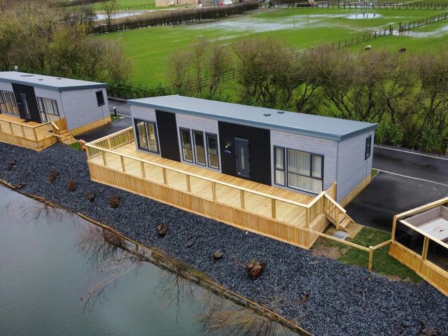A lodge with a wooden deck by a water body at Malton 2Bed Lodge Sleeps 4 Pet Friendly in Malton