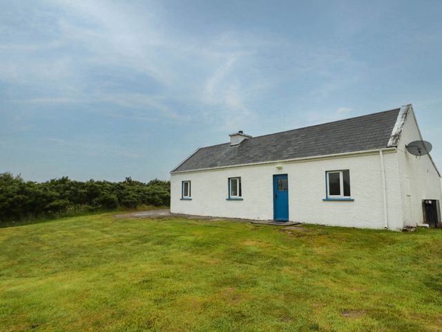 A house with a blue door and windows in a grassy area at Biddy Granny's