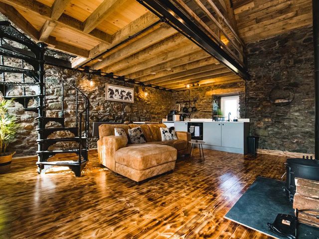 A living room with a sofa and spiral staircase at The Milking Shed at Pencraig Pet Friendly near Holyhead